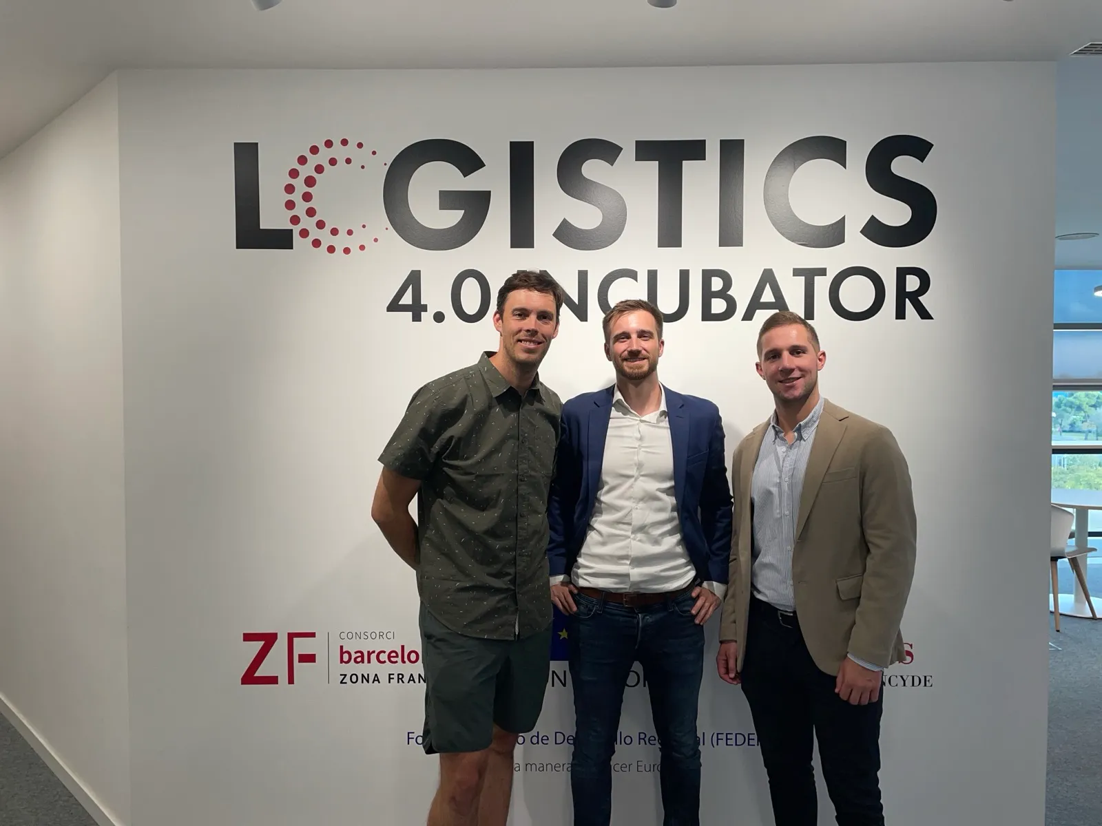 Els tres cofundadors de Grasshopper davant de la paret de la Incubadora Logística 4.0 de Barcelona, juny del 2024.